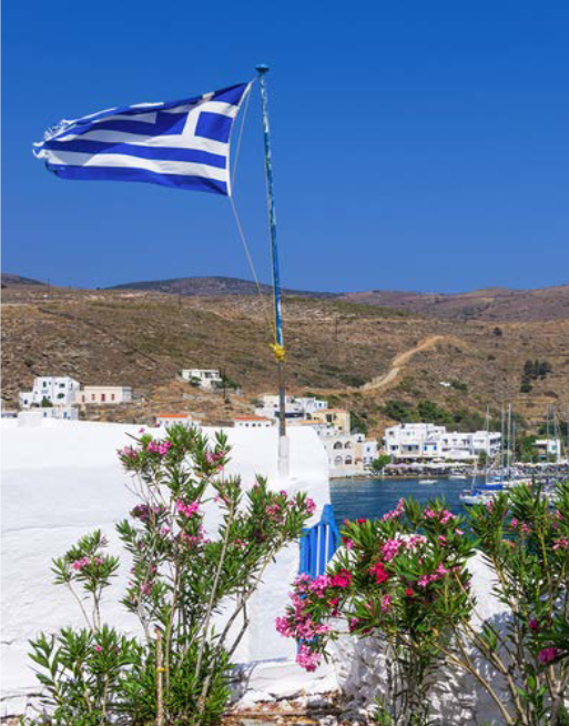 image of a village near the sea shore with a waving Greek flag
